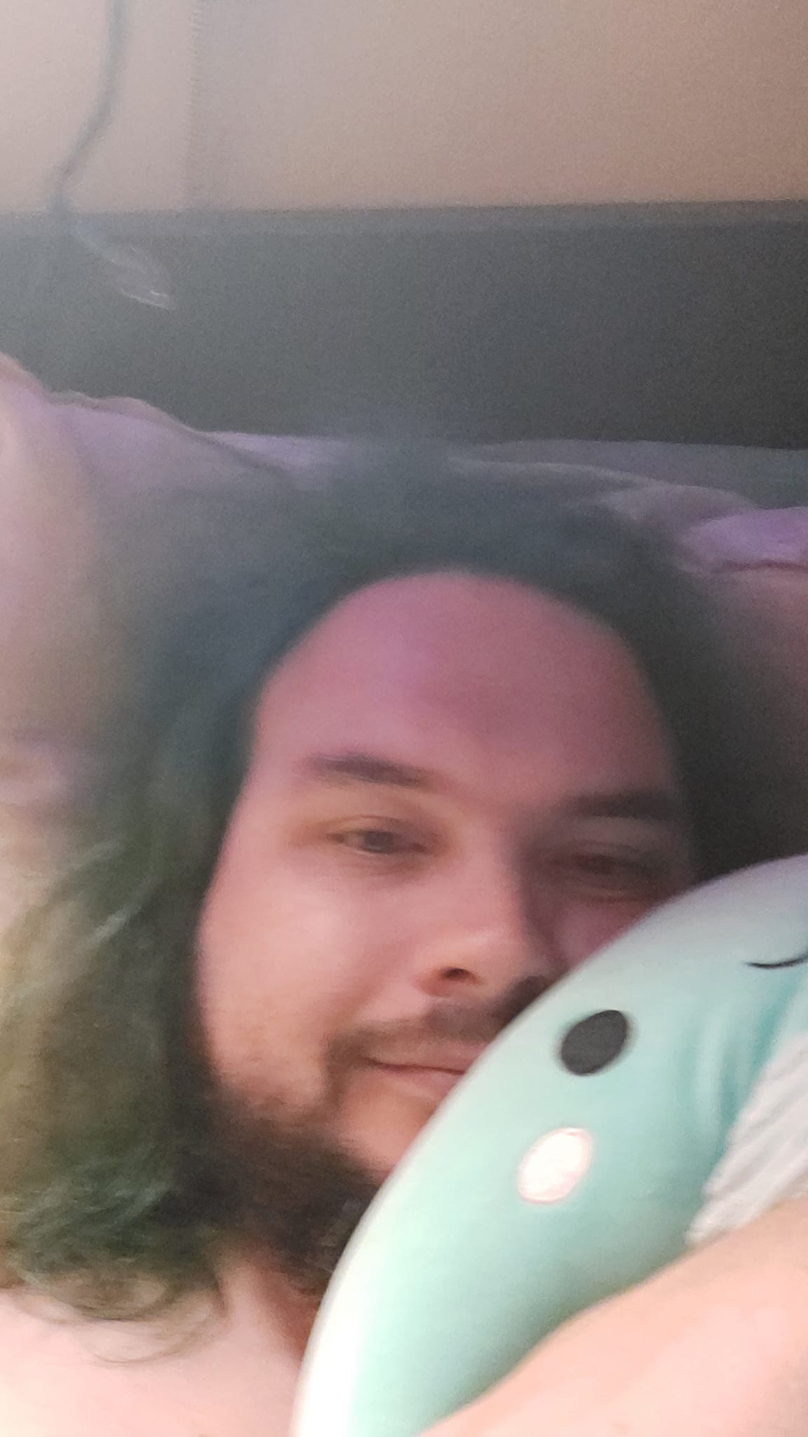 A man with green hair is holding a green Nessie Squishmallow, photo 3